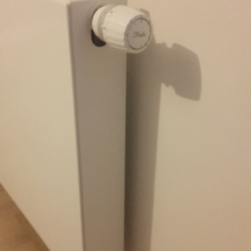 Radiator med termostat installeret som del af effektiv varmeløsning i bolig