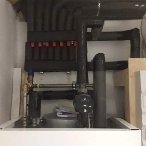 Varmeanlæg placeret i teknikskab med pumper og rørføring til opvarmning